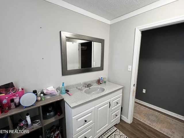 bathroom with baseboards, a textured ceiling, vanity, and wood finished floors