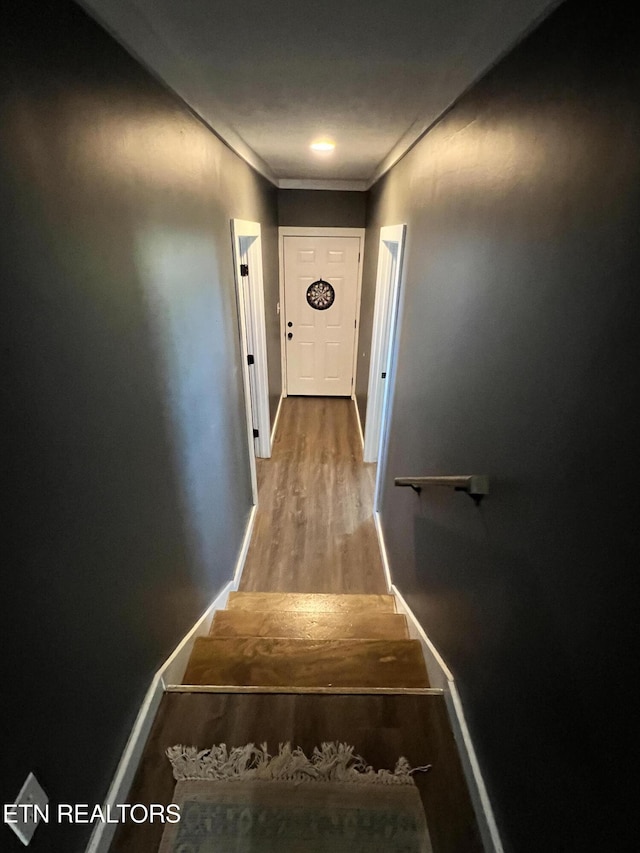 stairway featuring ornamental molding, baseboards, and wood finished floors