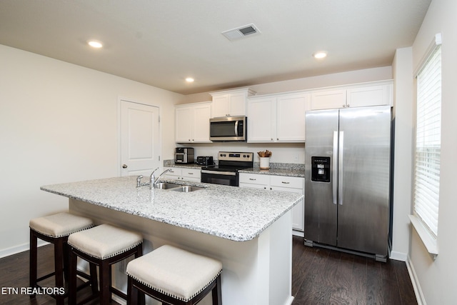 kitchen with appliances with stainless steel finishes, dark wood-style flooring, white cabinets, and a sink