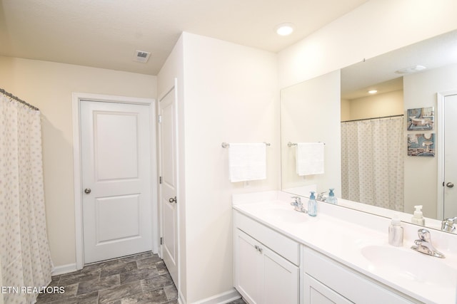 bathroom with recessed lighting, a sink, baseboards, and double vanity