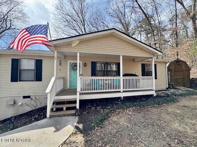 view of front of home featuring covered porch, a storage unit, crawl space, and an outdoor structure