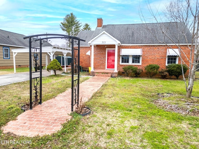 view of front of home with brick siding, roof with shingles, a chimney, a detached carport, and a front lawn