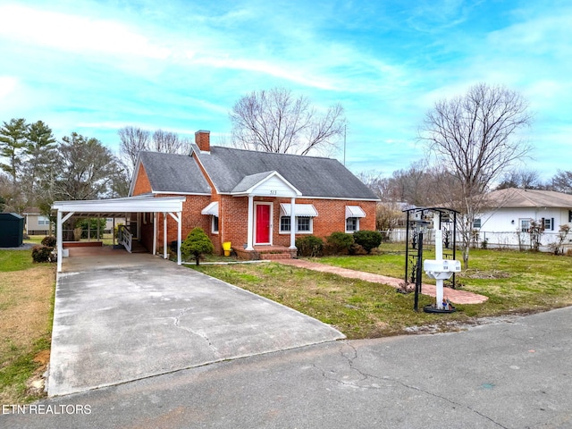 view of front of home featuring driveway, brick siding, a chimney, a carport, and a front yard