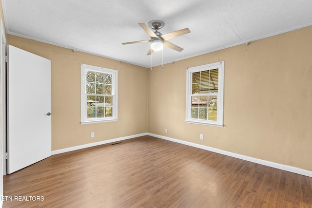 empty room with ceiling fan, a textured ceiling, baseboards, and wood finished floors