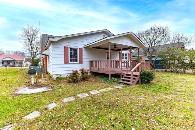 bungalow-style home featuring a front lawn, a ceiling fan, and a wooden deck