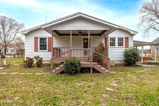 bungalow-style home with a ceiling fan, an attached carport, and a front lawn