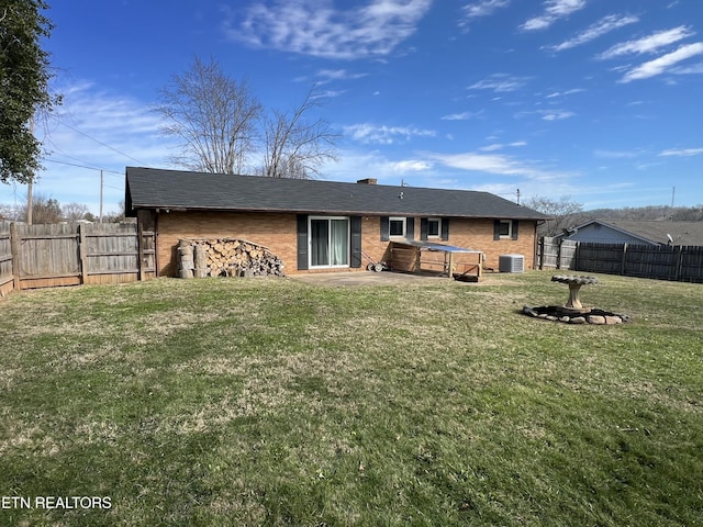 back of property featuring brick siding, a fenced backyard, cooling unit, and a yard