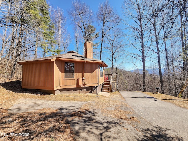 view of side of property with a shingled roof and a chimney