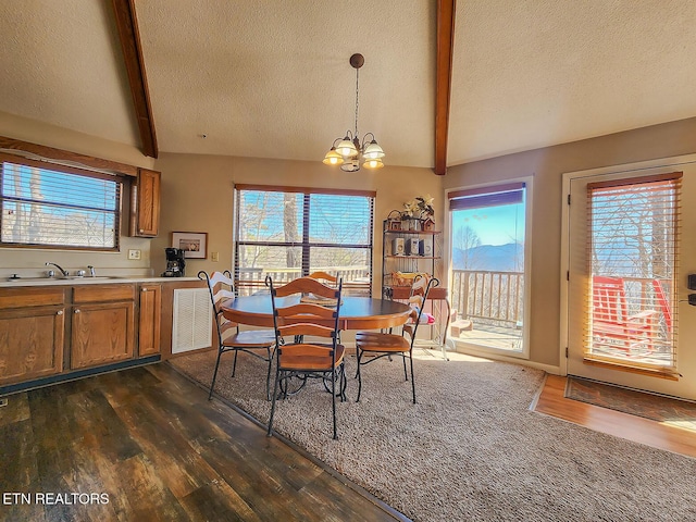 dining space featuring lofted ceiling with beams, dark wood-style floors, a textured ceiling, and a notable chandelier