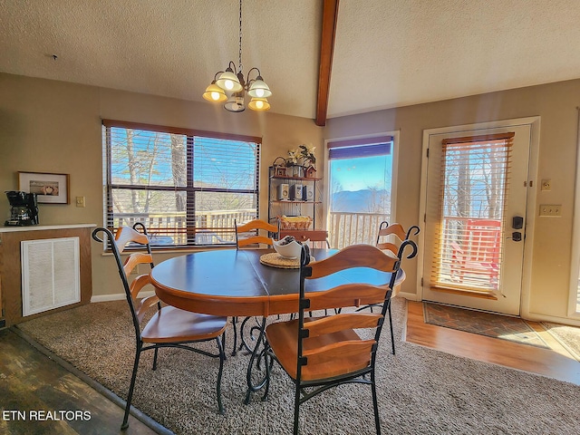 dining room featuring a healthy amount of sunlight, visible vents, beam ceiling, and wood finished floors