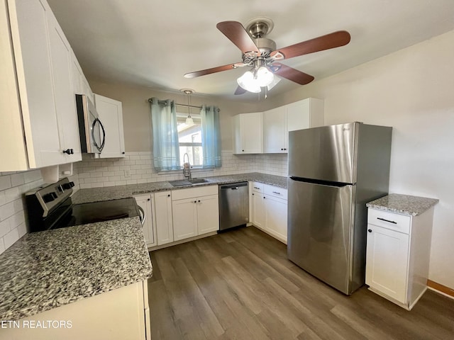 kitchen featuring a sink, backsplash, white cabinetry, appliances with stainless steel finishes, and dark wood-style flooring