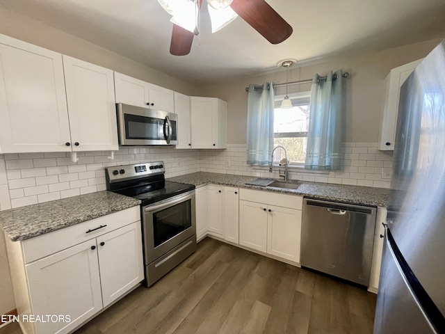 kitchen featuring stone counters, a sink, stainless steel appliances, dark wood-type flooring, and white cabinets