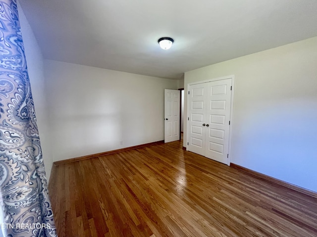 empty room with baseboards and wood finished floors