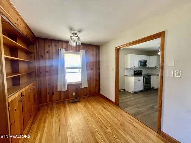 unfurnished dining area with baseboards and light wood finished floors