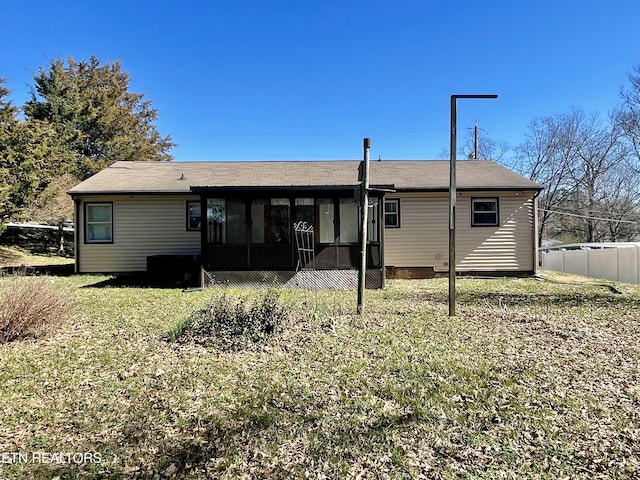 rear view of house with a yard, fence, and a sunroom