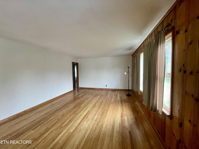 empty room with plenty of natural light, light wood-type flooring, and baseboards