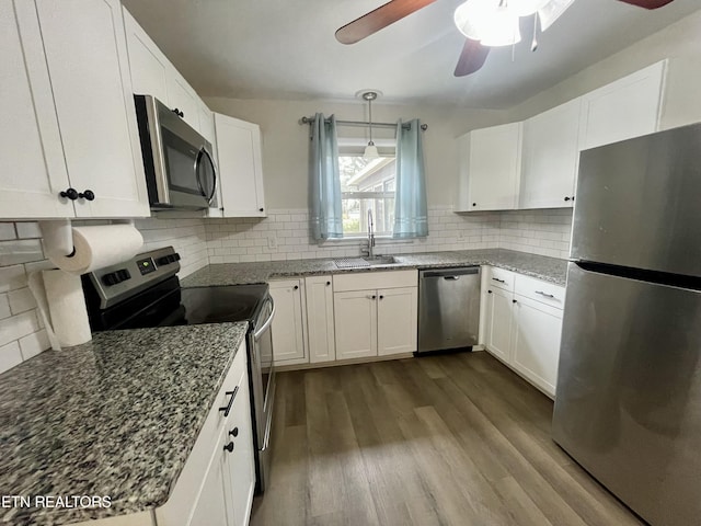 kitchen featuring dark wood-type flooring, decorative backsplash, white cabinets, stainless steel appliances, and a sink