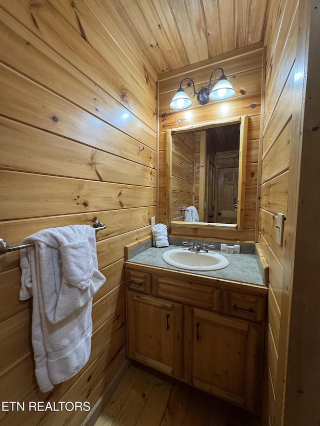 bathroom with wooden walls, vanity, and hardwood / wood-style flooring