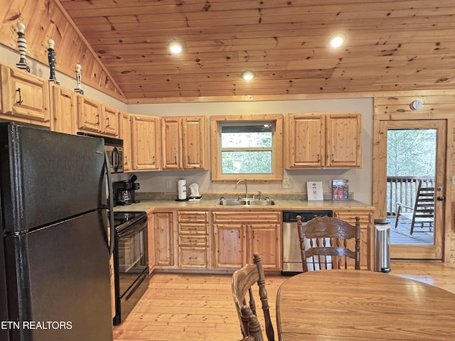 kitchen with lofted ceiling, light countertops, light brown cabinets, a sink, and black appliances