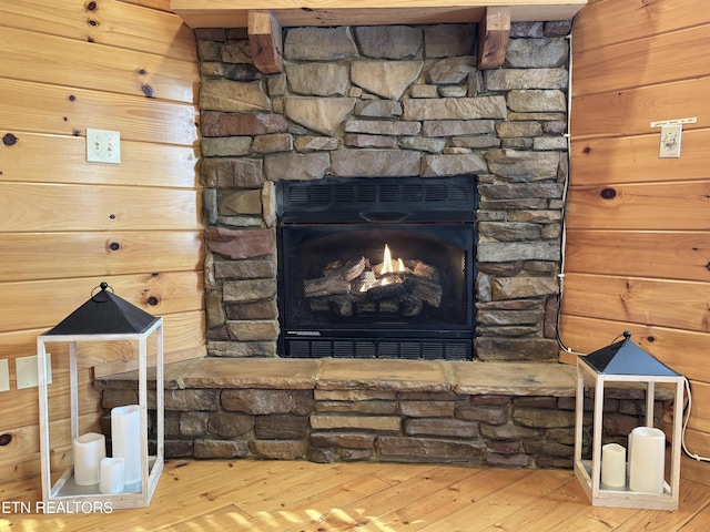 room details with wood walls, wood finished floors, and a stone fireplace