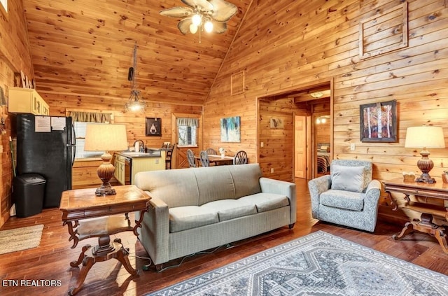 living area with hardwood / wood-style floors, wood walls, and a ceiling fan