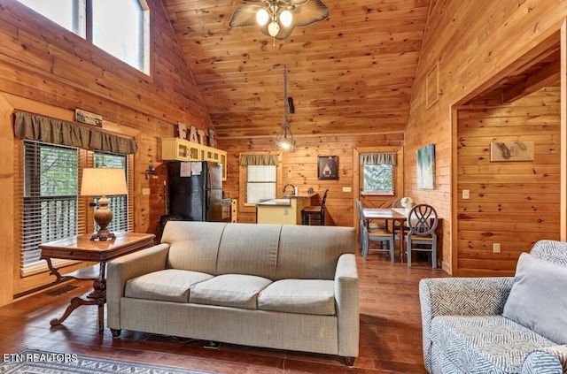 living room with high vaulted ceiling, wood walls, dark wood finished floors, and a ceiling fan