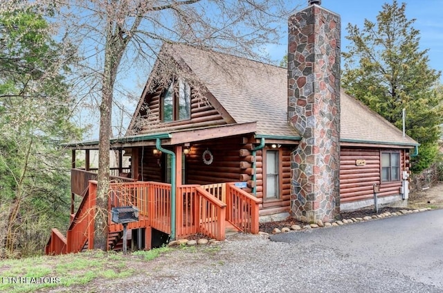 log cabin with roof with shingles, a chimney, and log siding