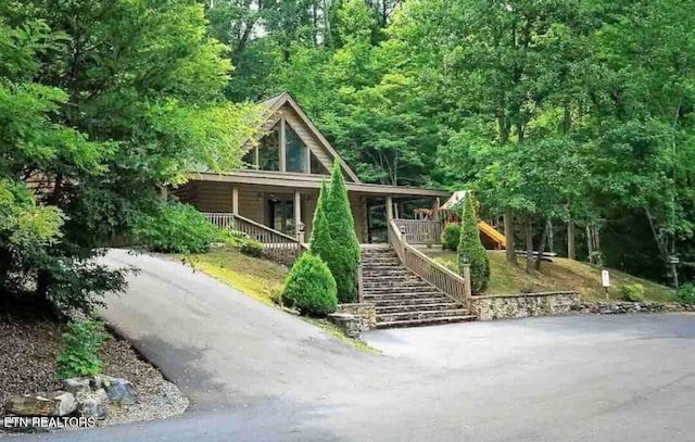 view of front of house featuring covered porch, stairway, and aphalt driveway