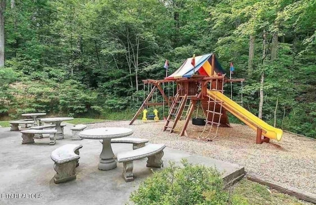 community jungle gym with a wooded view and a patio