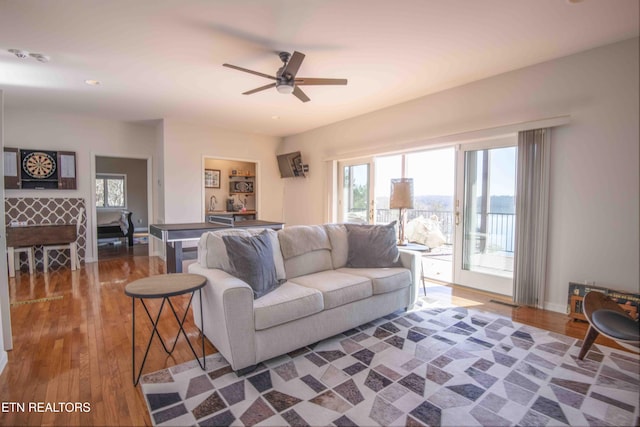 living room with ceiling fan, baseboards, and wood finished floors