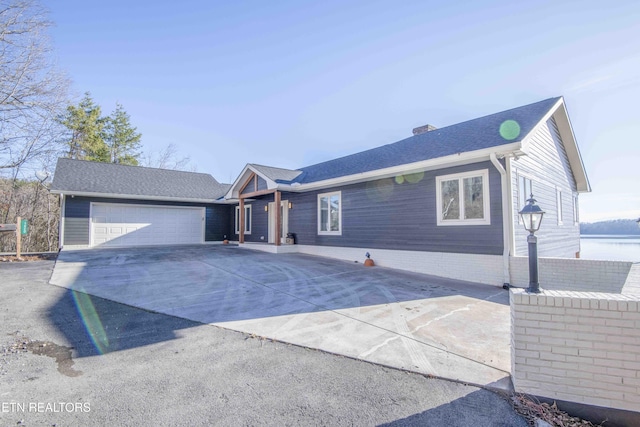 single story home featuring a garage, a chimney, concrete driveway, and roof with shingles