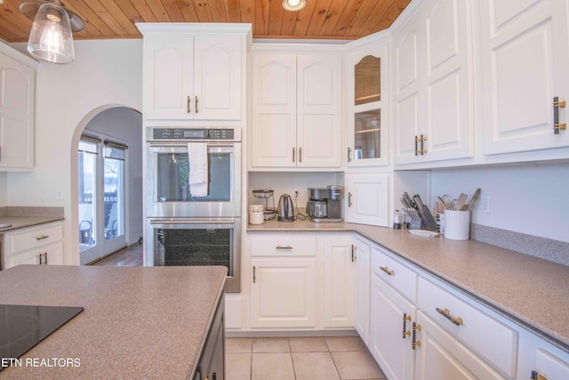 kitchen featuring arched walkways, black electric stovetop, stainless steel double oven, and wooden ceiling