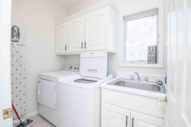 clothes washing area featuring a healthy amount of sunlight, cabinet space, washing machine and dryer, and a sink