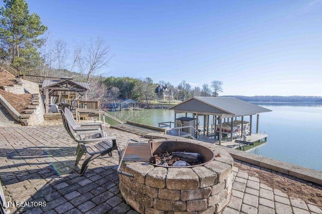 view of dock with a water view, an outdoor fire pit, and boat lift