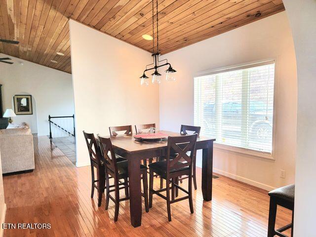 dining area featuring wood ceiling, wood-type flooring, baseboards, and vaulted ceiling