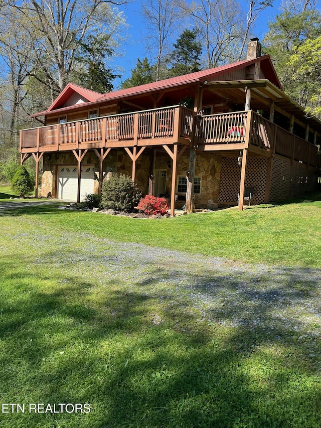 back of house featuring a deck, stone siding, a yard, and a chimney