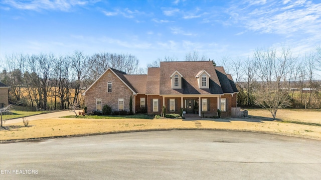 new england style home with a front yard and brick siding