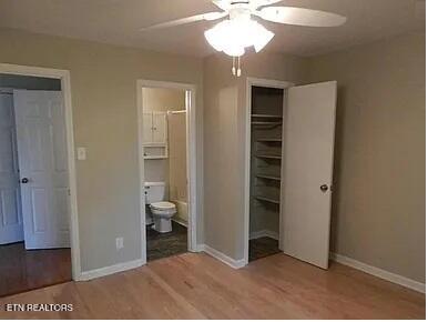unfurnished bedroom with baseboards, connected bathroom, a ceiling fan, and light wood finished floors