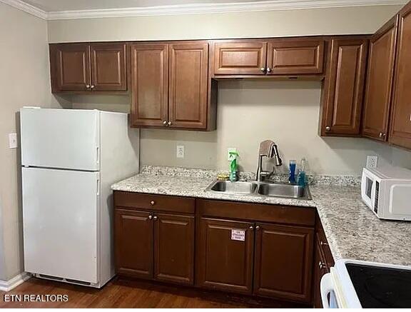 kitchen featuring white appliances, crown molding, a sink, and dark wood-style flooring