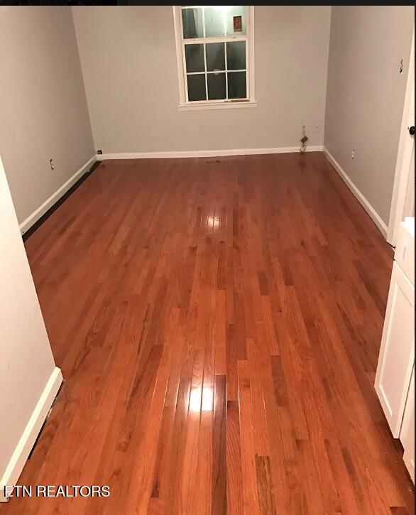 spare room with baseboards and wood finished floors