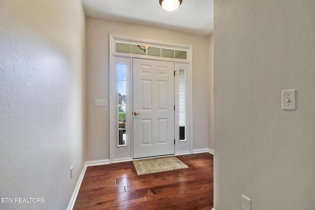 entryway featuring baseboards, dark wood finished floors, and a textured wall