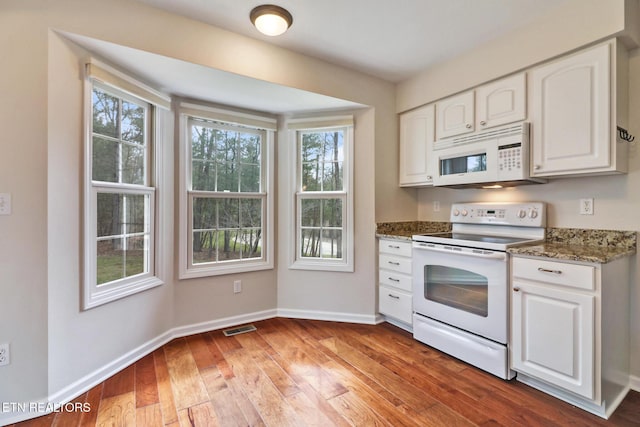 kitchen with stone counters, white appliances, visible vents, and white cabinets