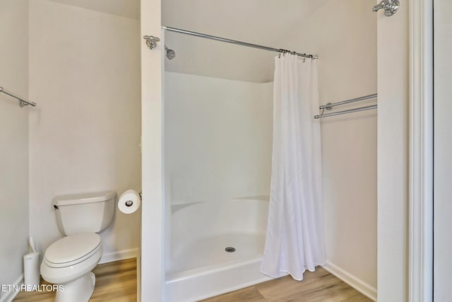 full bathroom featuring toilet, a shower with curtain, baseboards, and wood finished floors