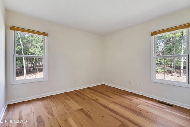 spare room featuring light wood-style floors, baseboards, and visible vents