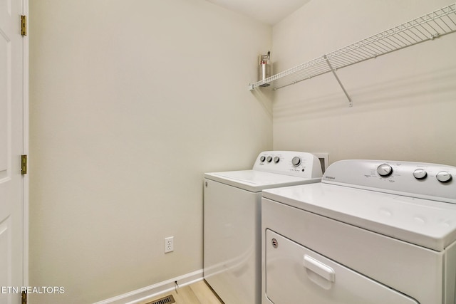 laundry room featuring light wood-type flooring, laundry area, baseboards, and washer and clothes dryer