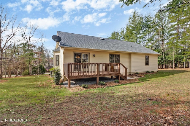 back of house with a deck, a yard, and roof with shingles