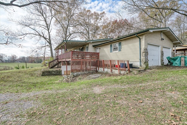 rear view of property with a garage, a yard, and a wooden deck