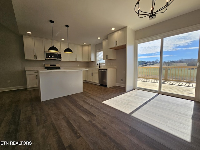 kitchen with dark wood-style flooring, light countertops, appliances with stainless steel finishes, a sink, and a kitchen island