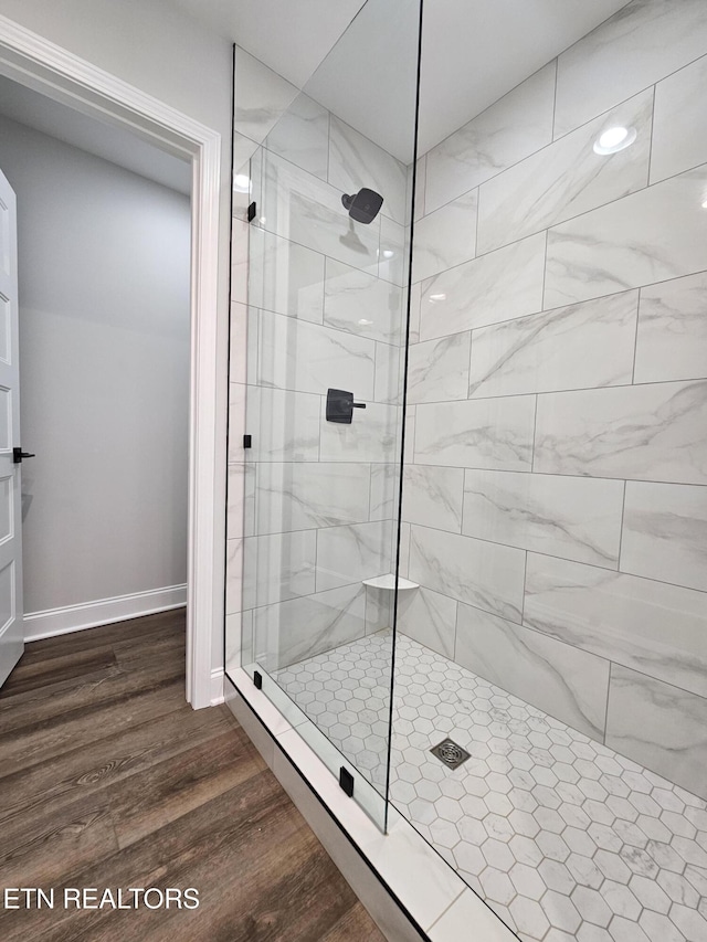 full bathroom featuring a tile shower, baseboards, and wood finished floors