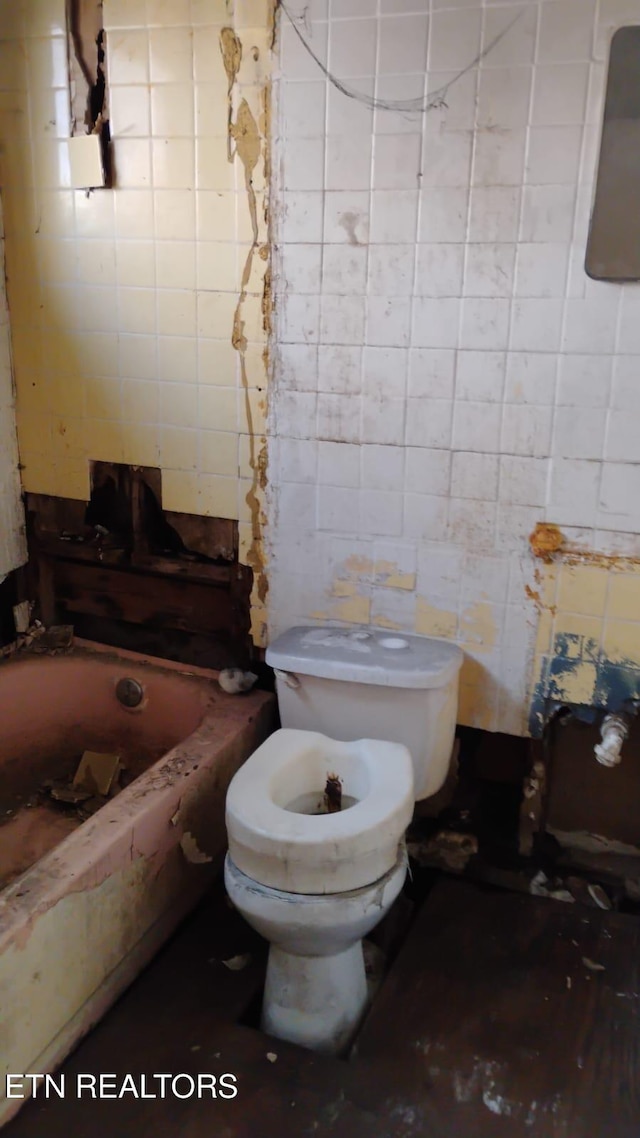 bathroom featuring a bathtub, tile walls, and toilet